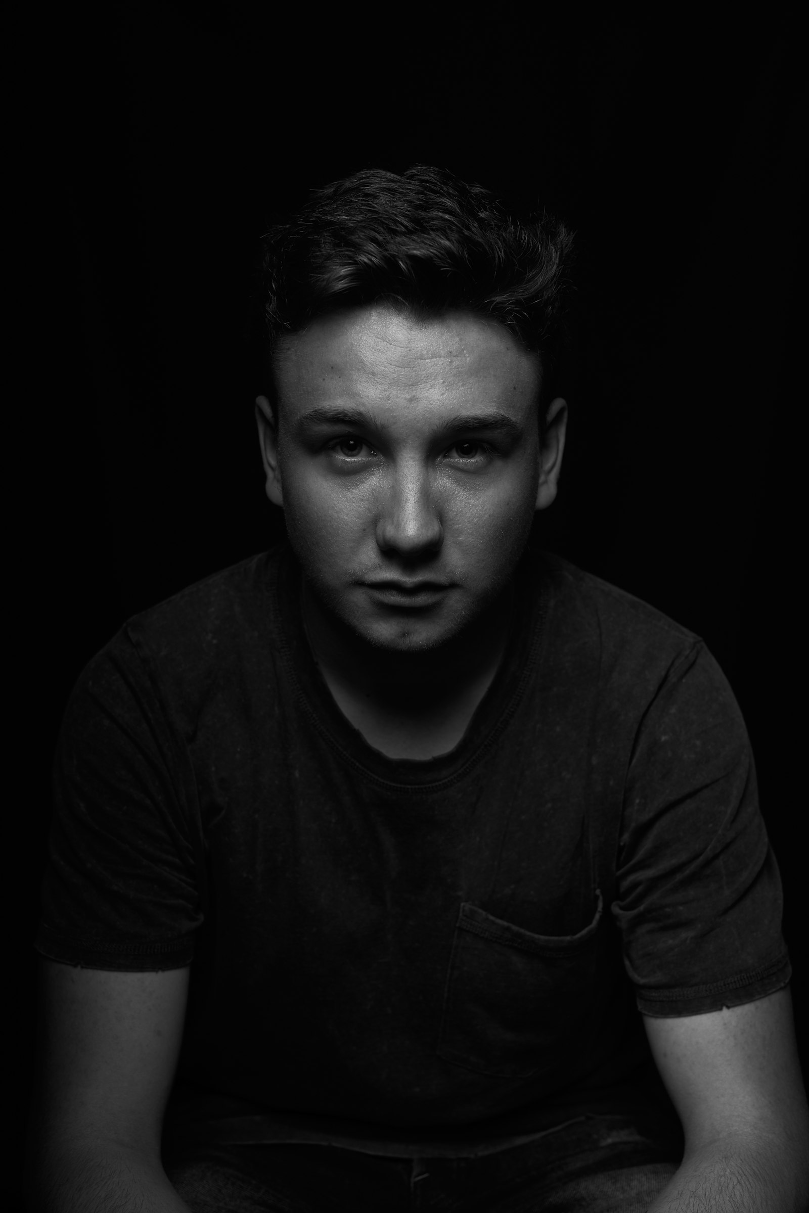 Black-and-white portrait of Mateo Ferreira seated against a black background