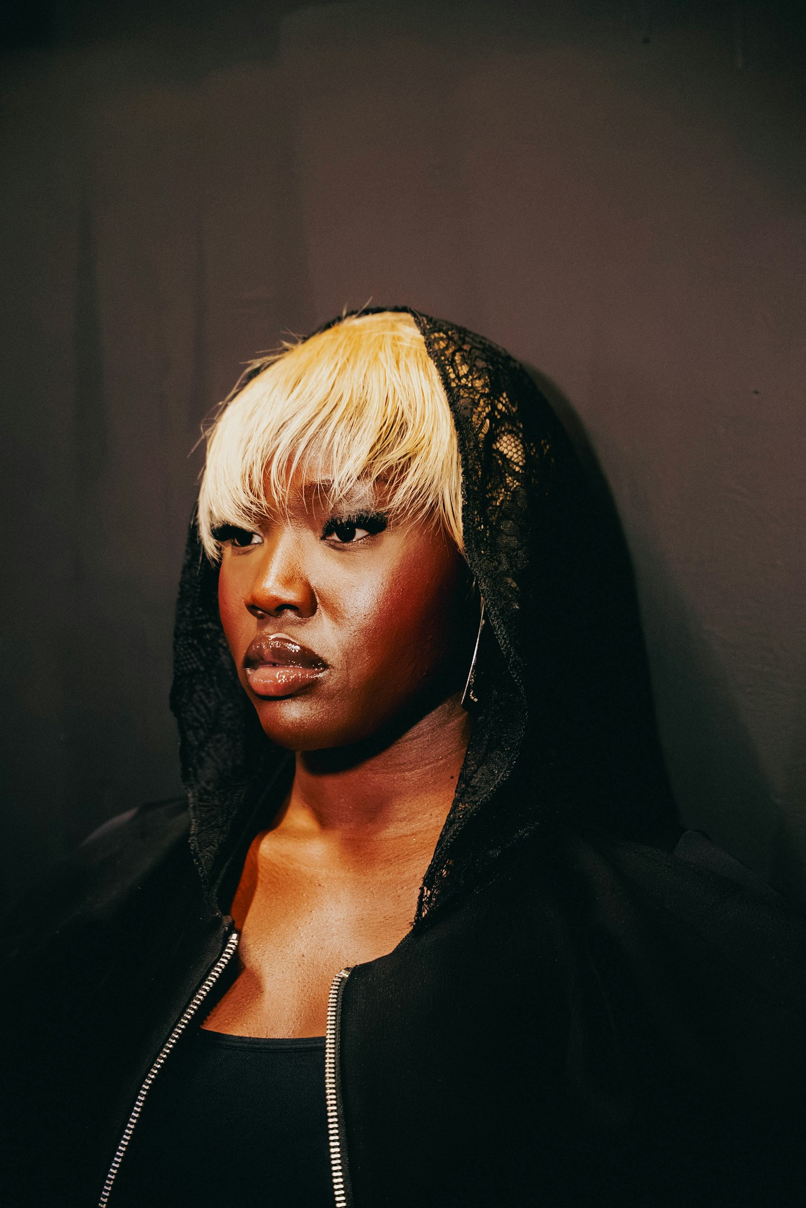 Imani Cole, photographed against a dark wall in a black jacket